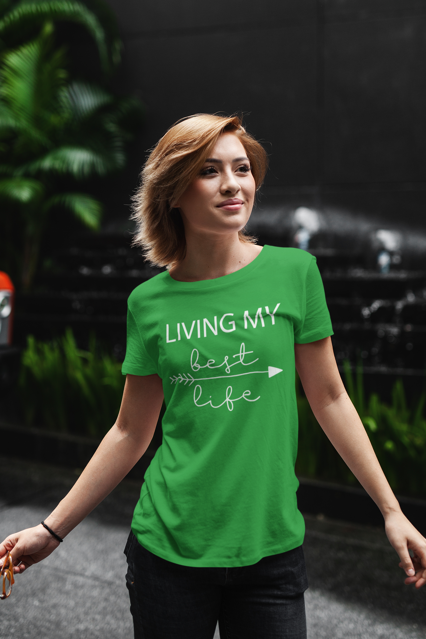 t-shirt-mockup-of-a-young-woman-standing-against-a-dark-background-with-some-plants-411-el
